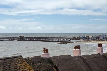 Idyllic pink, thatched, bay-windowed cottage on the seafront